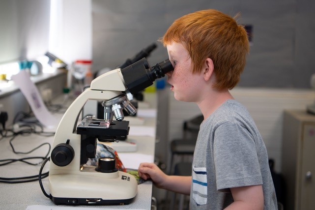a young boy looking down a microscope