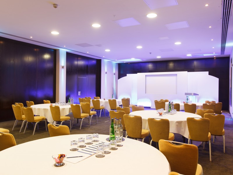 high class conference setting. round tables with white table cloths and amber lighting