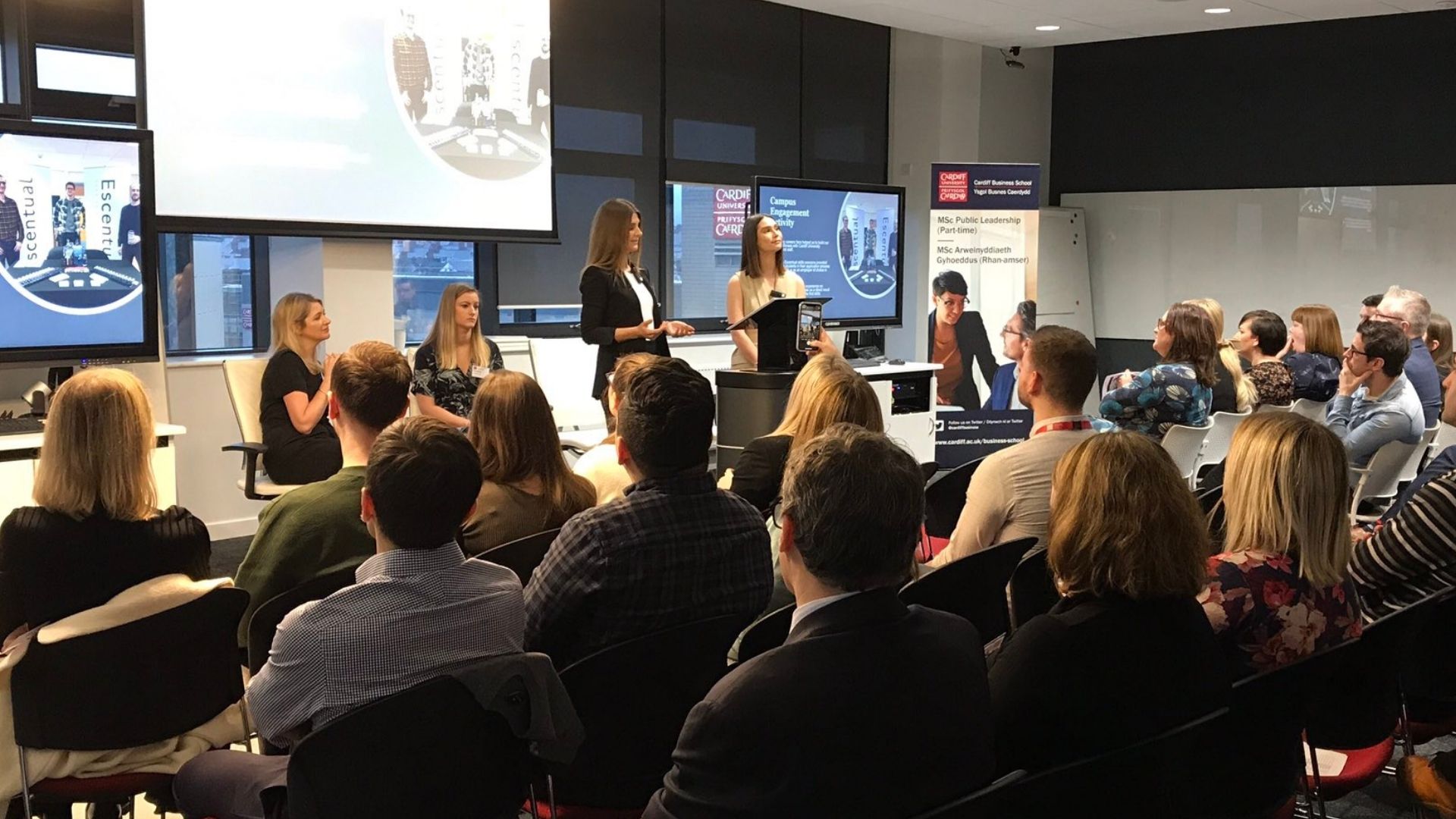 Two young women present in lecture space