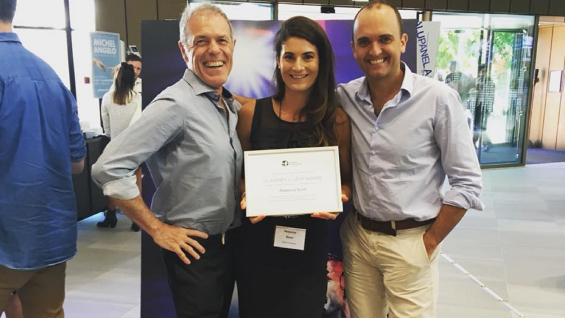 Woman poses with award and two men