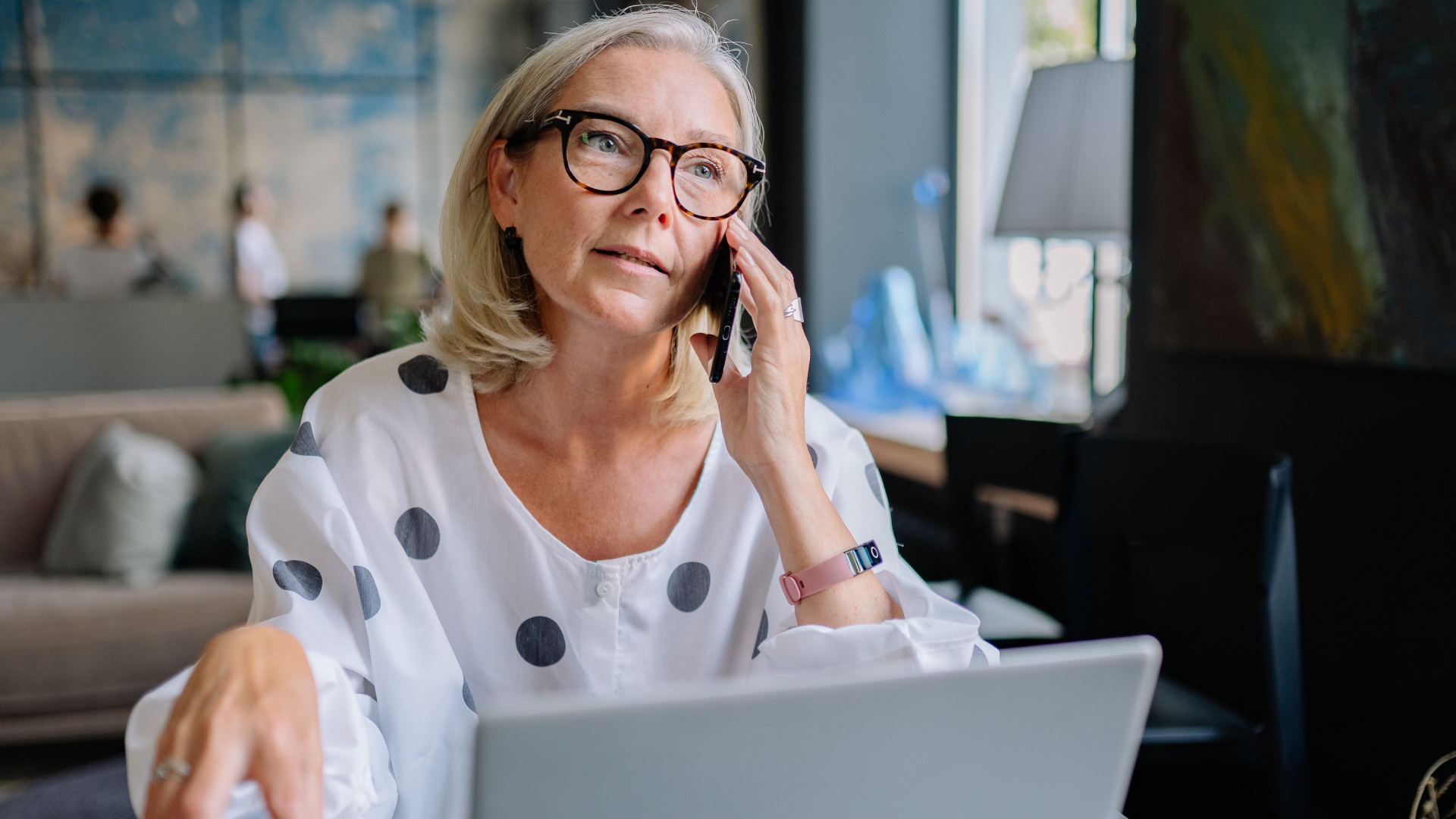 Woman Sitting at Table with Laptop while Talking on Phone