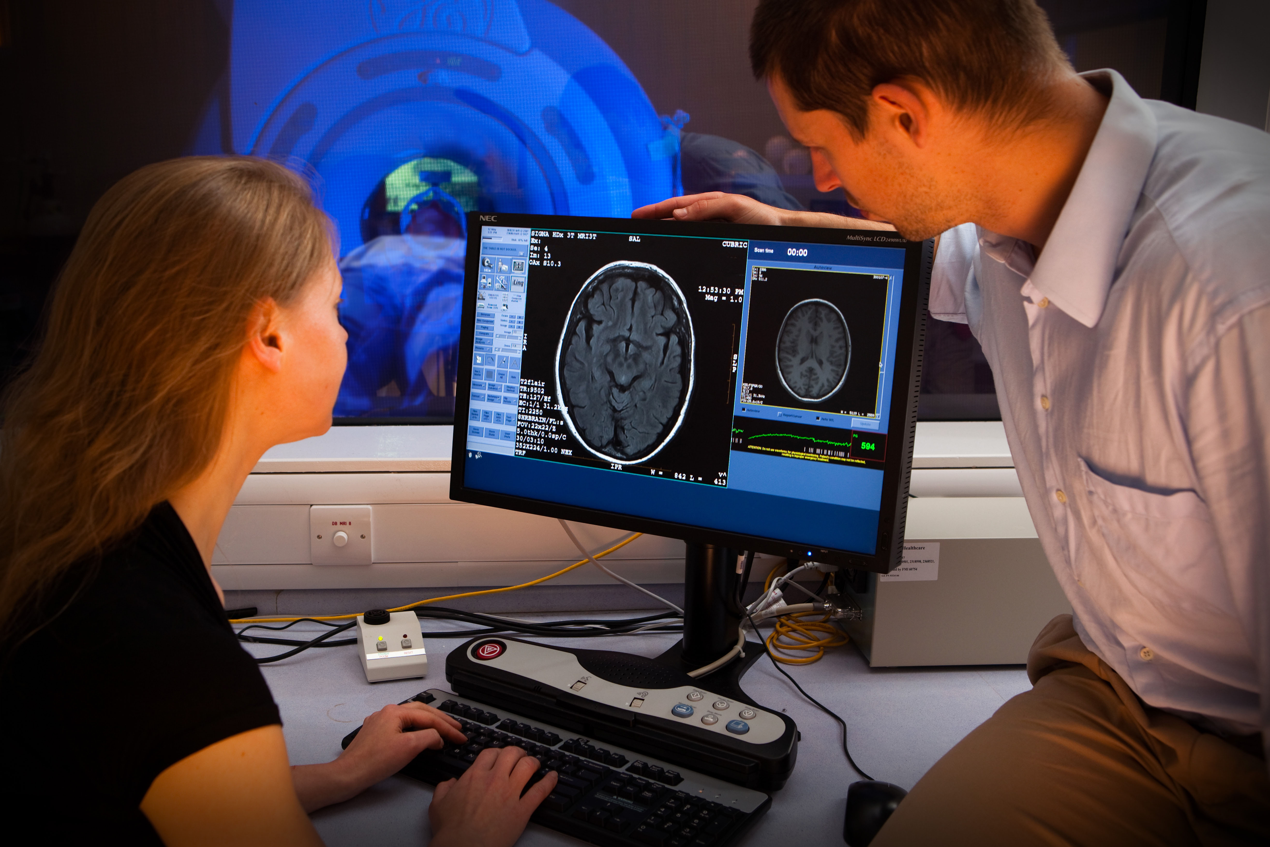 screen showing a brain scan with 2 people looking at it 