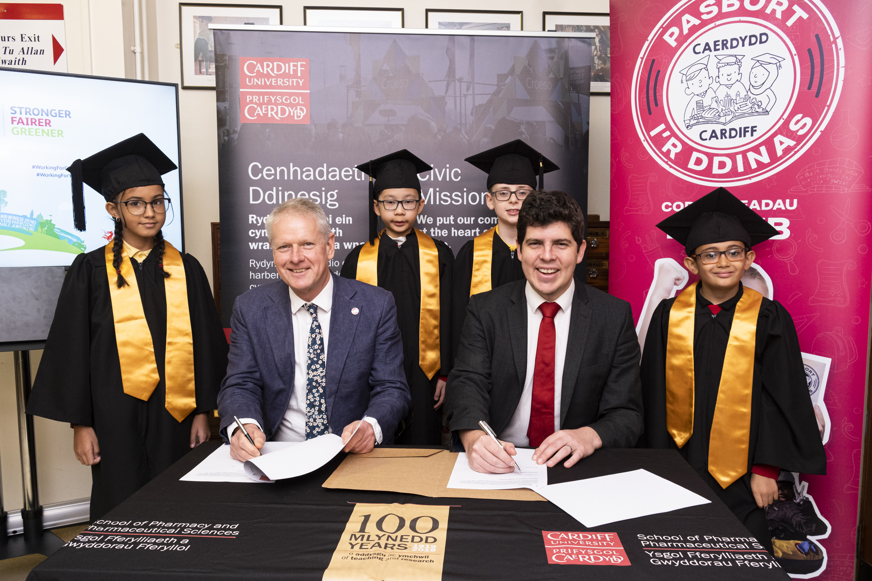 Colin Riordan and Huw Thomas surrounded by school children dressed in graduation outfits
