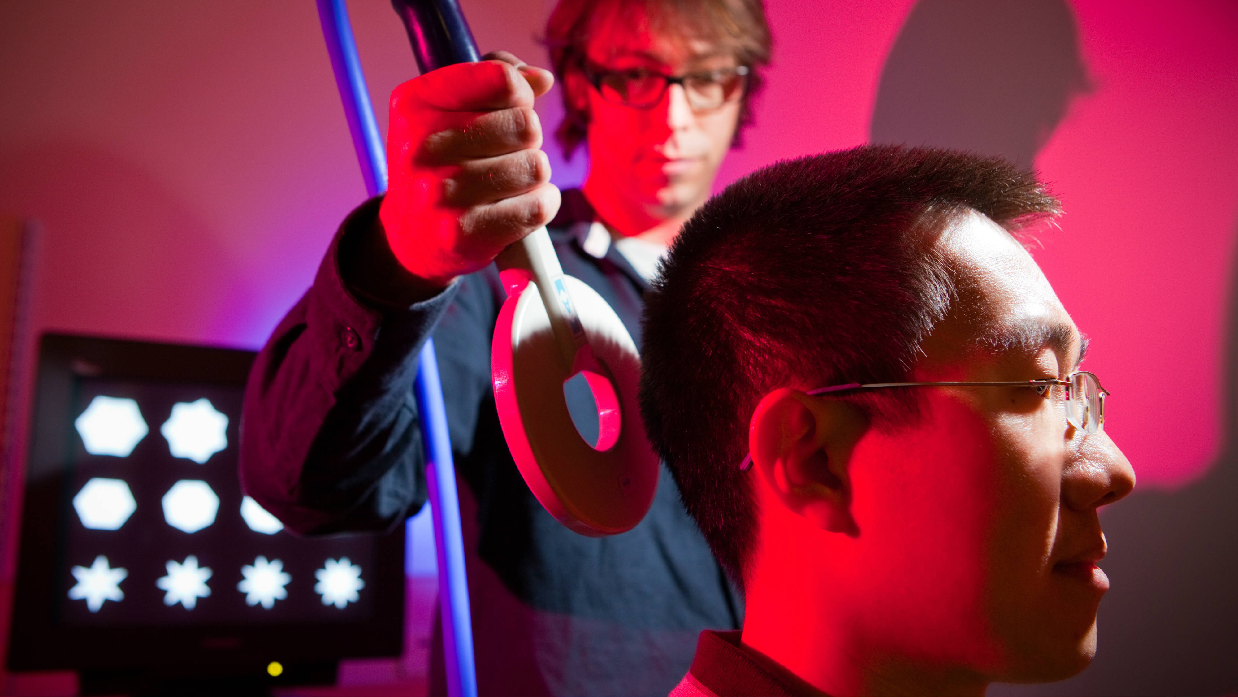 Man with a transcranial electrical stimulation wand behind his head 