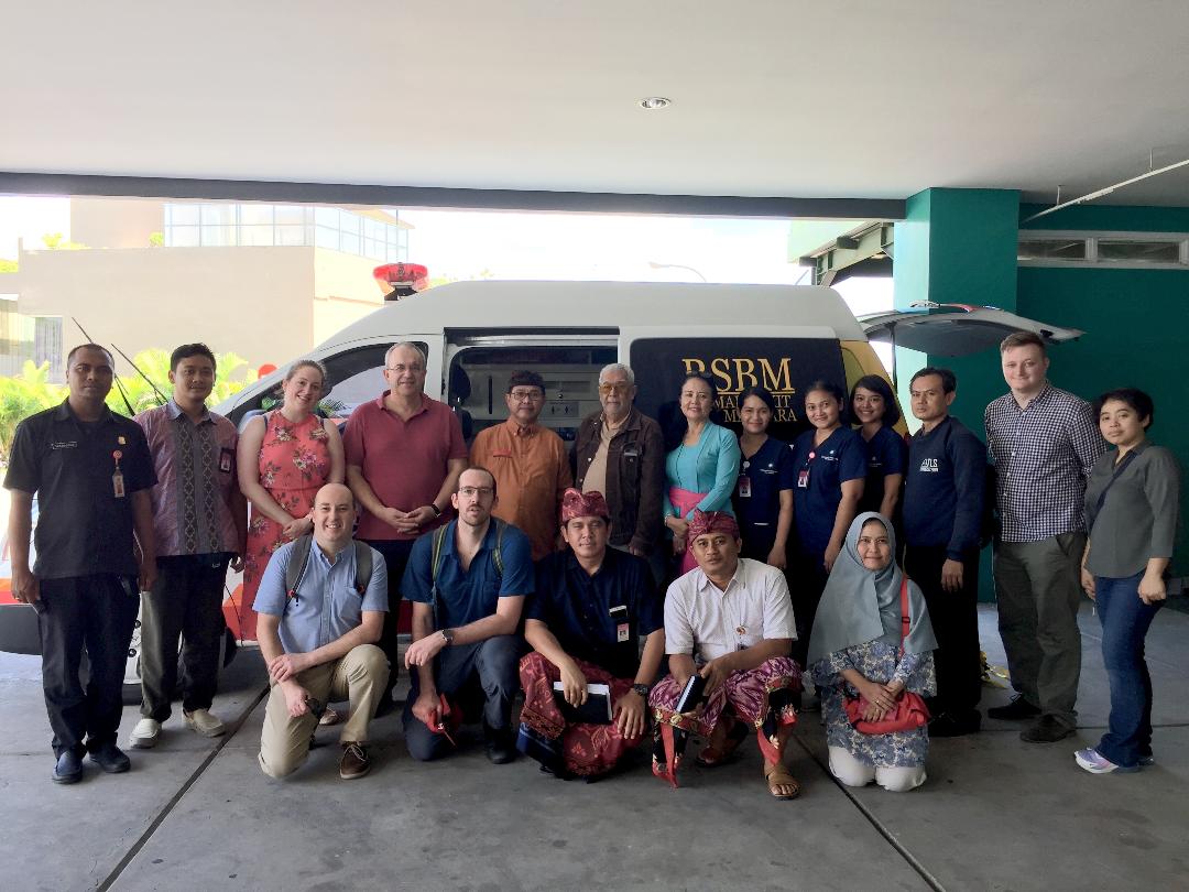 Group of people from Indonesian and Wales standing in front of an Indonesian ambulance