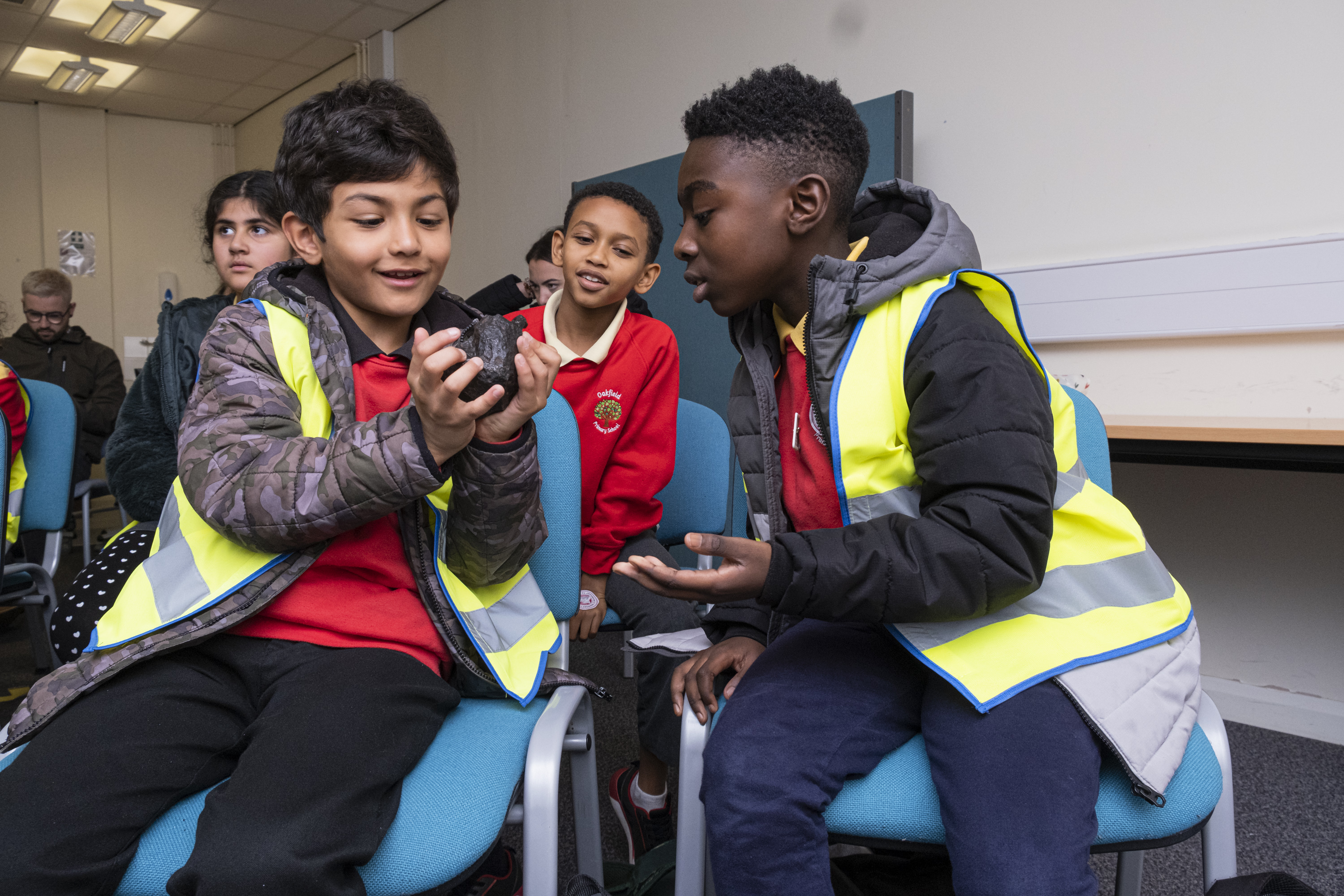 Two schoolboys examine a rock as they're watched by classmates