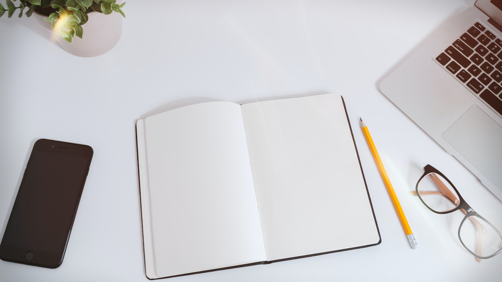 White work table with notes, smartphone and laptop