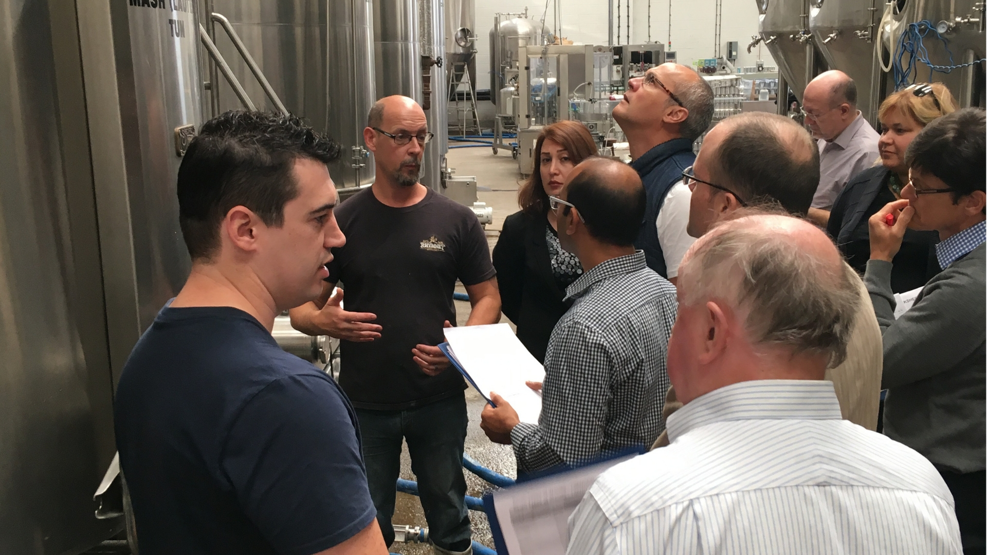 People gathered around brewing equipment