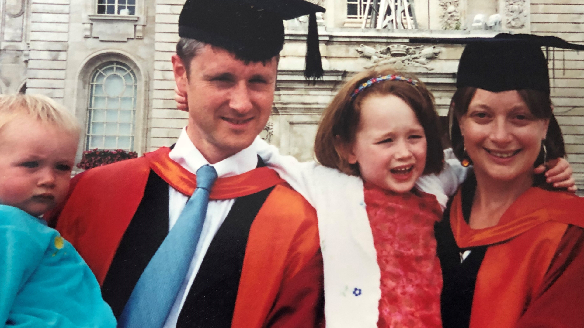 Two people with their children in graduation robes