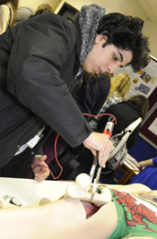 A pupil removing a femur from a model human body